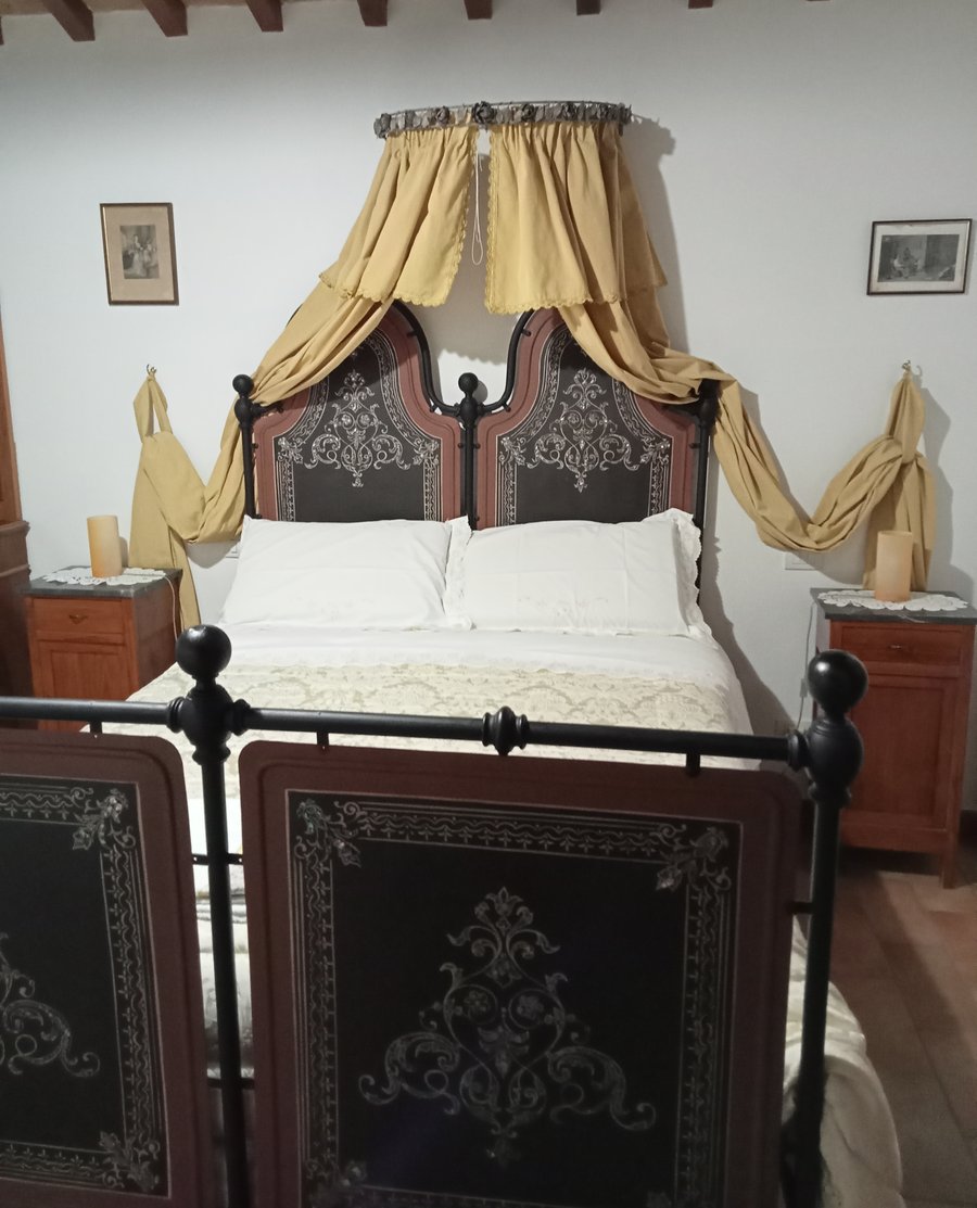 Camera con letto in ferro battuto e travi a vista per il pernottamento con prima colazione ad Assisi